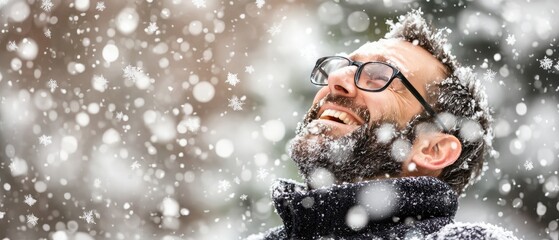 Joyful man laughing while enjoying snowfall in winter landscape, with snowflakes falling around him in a serene outdoor setting