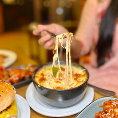 Close up of a delicious cheesy pasta dish being lifted with a fork showcasing melted cheese and noodles in a restaurant setting