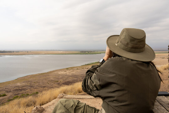 Tourist with binoculars views the vast landscape and wetlands of Amboseli National Park Kenya