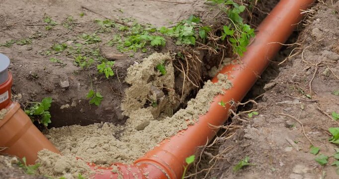 Laying sewer pipe and backfilling the trench with sand. Installing an external sewer system in a private home. 4K slow-motion video