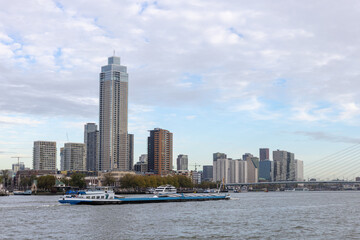 Sailing cargo ship with the Rotterdam skyline and the Erasmus Bridge in the background