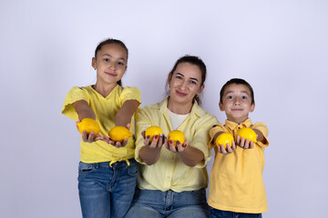 A woman and two children are holding yellow lemons