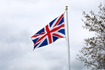 Obraz premium United Kingdom flag waving naturally in the wind, showing movement, colour, and national identity in a clear outdoor scene.