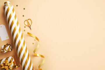Flat lay of gold and white striped wrapping paper, ribbon, scissors, and small gift boxes. Christmas gift wrapping. Copy space.