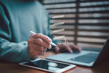 Businessman signing digital document using stylus pen on tablet with laptop, modern technology concept for e-signature, online contract, remote work, and paperless office efficiency.