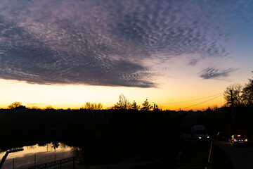 Cloudy sky above sunset horizon with silhouettes of trees. Outdoor landscape photography. Evening sky and weather concept.