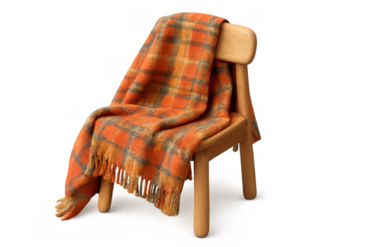 Orange wool plaid throw blanket draping over rustic wooden chair, creating cozy homely comfort with fall autumn vibes
