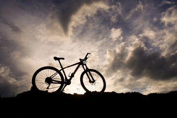 Obraz premium Silhouette of a Mountain Bike: A striking silhouette of a mountain bike stands dramatically against a dynamic sky backdrop, suggesting adventure, freedom, and the thrill of outdoor exploration. 