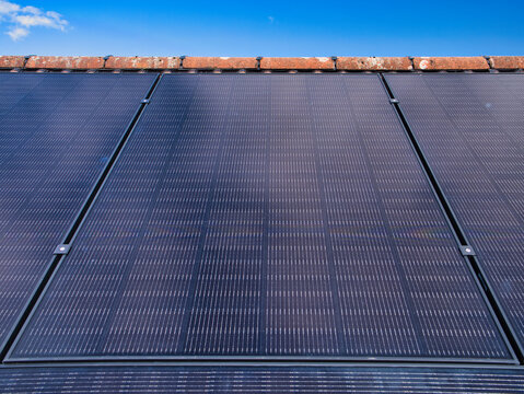Close-up of residential solar panels on a house roof under a clear blue sky in the UK, capturing clean power and modern home efficiency.