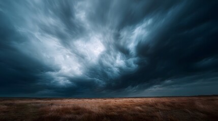 Obraz premium A dramatic vista of dark turbulent storm clouds gathering over a vast dry golden grassy field under an intense atmospheric sky