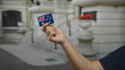 Man holding australian flag embroidery outdoors on a city street showcasing national pride and cultural heritage.