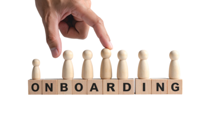 Hand selects wooden figure atop "ONBOARDING" blocks, symbolizing a new hire's integration