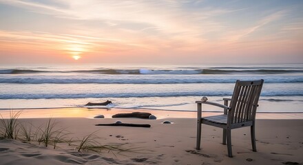 Empty wooden chair on beach at sunrise overlooking ocean waves