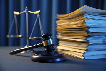 Judge's gavel, stack of papers and scales.