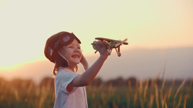 little boy in pilot hat holding wooden airplane in sunset light cinematic slow motion concept of happy childhood freedom dream imagination and future adventure lifestyle