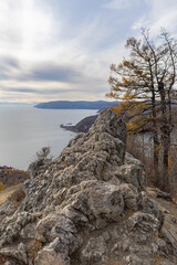 Chersky stone viewpoint with view of the Angara river at lake Baikal in Listvyanka village in autumn. Rocky cliffs overlooking calm waters with autumn trees and distant coastline,