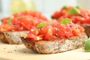 Tasty bruschettas with tomatoes and basil on wooden table, closeup