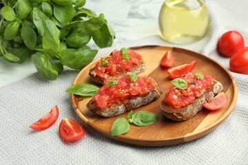 Tasty bruschettas with tomatoes and basil on white marble table, closeup