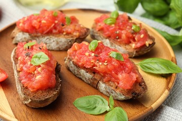 Tasty bruschettas with tomatoes and basil on table, closeup