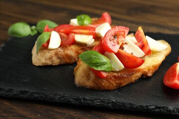Tasty bruschettas with mozzarella cheese, tomatoes and basil on wooden table, closeup