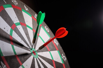 Dartboard with darts on black background, closeup. Space for text