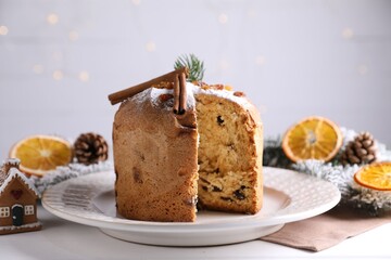 Christmas food. Delicious Panettone cake and festive decor on white wooden table against background with blurred lights, closeup