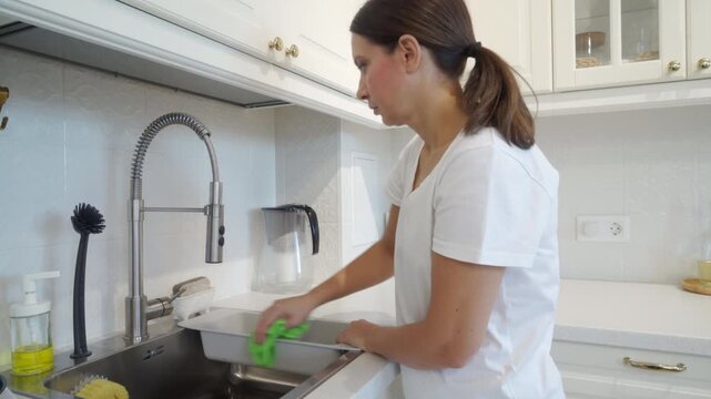 Wet cloth wipes plastic and stainless steel sink components. The cloth rubs the surface, creating a wet squish and faint swish.