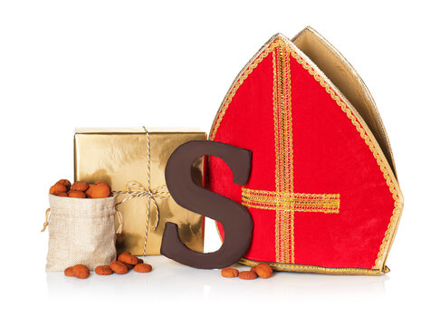 Saint Nicholas (Sinterklaas) day. Red mitre, chocolate letter S and other traditional treats isolated on white