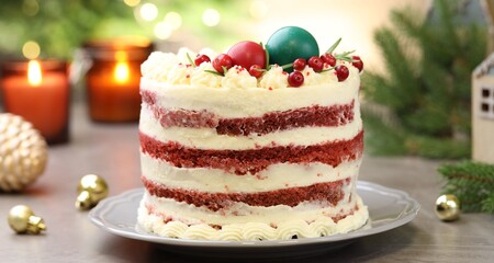 Delicious sponge cake with Christmas decor and red currants on grey textured table against blurred lights, closeup. Bokeh effect