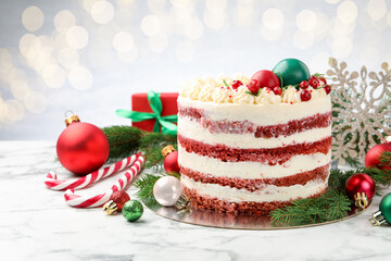 Delicious sponge cake with Christmas decor and red currants on white marble table against grey background, closeup. Bokeh effect