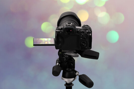 Professional camera against blurred lights, bokeh effect