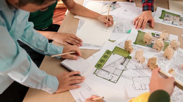 Architect and safety engineer discussion about building construction use blueprint on table with architectural document, measurement tool and wooden block scatter around at modern office. Delineation.
