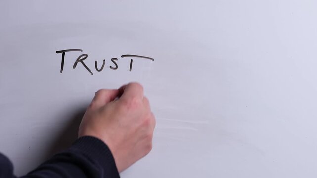 A person is writing Trust in God in black marker pen on a whiteboard, perfect for Christian, religious themes, Church communications or faith presentations
