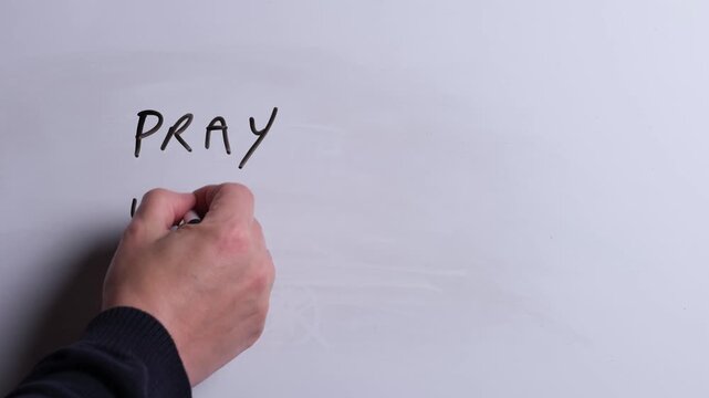 A person is writing Pray Without Ceasing in black marker pen on a whiteboard, perfect for Christian, religious themes, Church communications or faith presentations