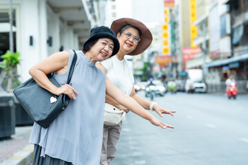 Senior asian women travelers laughing posing on busy street showing friendship happiness and joy representing positive retirement lifestyle freedom and travel together experience