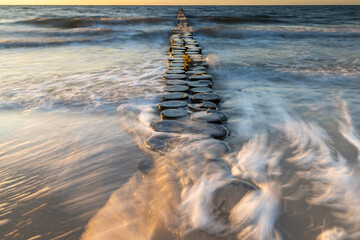 Buhnen in Wustrow an der Ostsee bei Sonnenuntergang mit Wellen in der Langzeitbelichtung