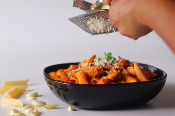 Penne pasta in red sauce topped with grilled chicken, grated cheese, and parsley