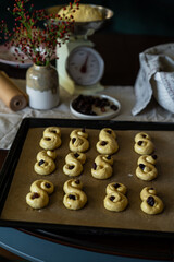 Process of making traditional Swedish saffron buns. Raw S-shaped yeast buns spiced with saffron and decorated with raisins on baking tray before baking.