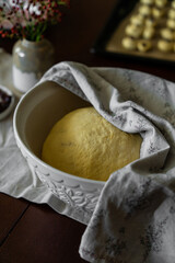 Process of making traditional Swedish saffron buns. Yeast dough spiced with saffron rising in white bowl covered with linen napkin.