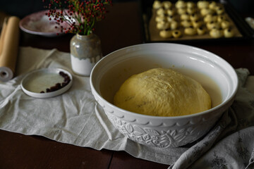 Holiday baking. Yeast dough spiced with saffron rising in white bowl covered with linen napkin. 