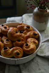 Homemade Swedish saffron buns on wooden table. Traditional treat eaten on Saint Lucia Day and during Advent. Spiced with saffron and decorated with raisins.