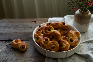 Homemade Swedish saffron buns on wooden table. Traditional treat eaten on Saint Lucia Day and during Advent. Spiced with saffron and decorated with raisins.