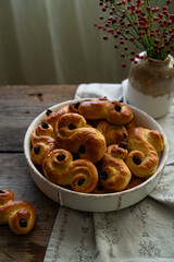 Homemade Swedish saffron buns on wooden table. Traditional treat eaten on Saint Lucia Day and during Advent. Spiced with saffron and decorated with raisins.