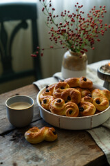 Homemade Swedish saffron buns and coffee on wooden table. Traditional treat eaten on Saint Lucia Day and during Advent. Spiced with saffron and decorated with raisins.