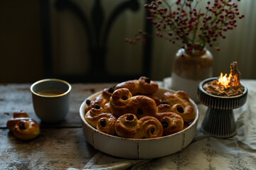 Homemade Swedish saffron buns and coffee on wooden table. Traditional treat eaten on Saint Lucia Day and during Advent. Spiced with saffron and decorated with raisins.
