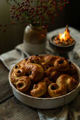 Homemade Swedish saffron buns and coffee on wooden table. Traditional treat eaten on Saint Lucia Day and during Advent. Spiced with saffron and decorated with raisins.