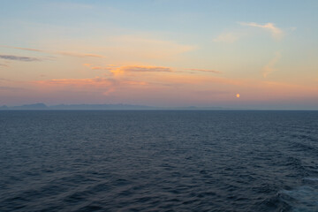 seascape at sunset with the moon low in the sky
