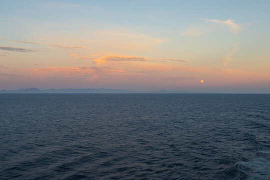 seascape at sunset with the moon low in the sky - Powered by Adobe