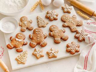 Homemade Christmas gingerbread men cookies with Ingredients for cooking Christmas baking on white wooden background table. Top view. Christmas holiday kitchen background. Design element.