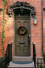 Beautiful brown door adorned with a wreath and ivy, showcasing classic architectural details in a warm urban setting